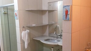 Une salle de bain équipée d’un lavabo, d’un miroir, d’un porte-serviettes, d’une douche et d’un tapis vert.