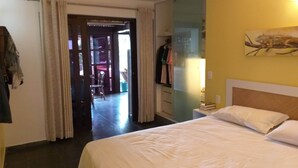 Une chambre d’hôtel comprenant un lit, une armoire, un miroir et une porte donnant sur un balcon.