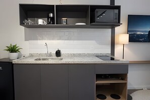 A modern kitchen with a built-in microwave, coffee maker, and a small shelf.