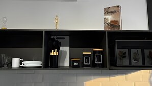 Un plan de travail de cuisine avec une machine à café, une tasse blanche et divers ustensiles de cuisine.
