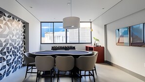 Une salle de réunion moderne, dotée d’une table ronde, de chaises et offrant une vue sur la ville grâce à de grandes fenêtres.
