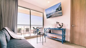 A modern living room with a sofa, a small table, a blue console table, and a large window with a view of the city. - Villa Lili, Apartamento lujoso frente al mar, en Santa Marta Colombia (santa marta)