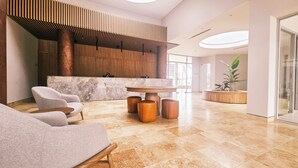 A modern lobby with a reception desk, seating area, and a large plant. - Villa Lili, Apartamento lujoso frente al mar, en Santa Marta Colombia (santa marta)