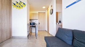 A modern living area with a sofa, a kitchen in the background, and a wall clock. - Villa Lili, Apartamento lujoso frente al mar, en Santa Marta Colombia (santa marta)