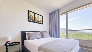 A modern hotel room with a large bed, a nightstand, a painting, and a view of the landscape. - Villa Lili, Apartamento lujoso frente al mar, en Santa Marta Colombia (santa marta)