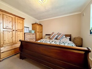 Ein Schlafzimmer mit einem hölzernen Bett, einem Kleiderschrank, einer Kommode und einer Wanduhr.