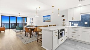A modern kitchen with white cabinetry, a dining area with a view, and a balcony with a view. - Fully remodeled ocean front condo with views, pool (Navarre)