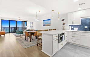 Eine moderne Küche mit weißen Schränken, ein Essbereich mit Aussicht und ein Balkon.
