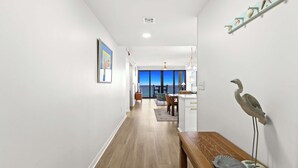 A hallway with a wooden bench, a framed picture, and a wall-mounted shelf with decorative items. - Fully remodeled ocean front condo with views, pool (Navarre)