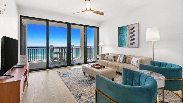 A living room with a sofa, two armchairs, a coffee table, a TV, and a balcony with a view of the ocean. - Fully remodeled ocean front condo with views, pool (Navarre)