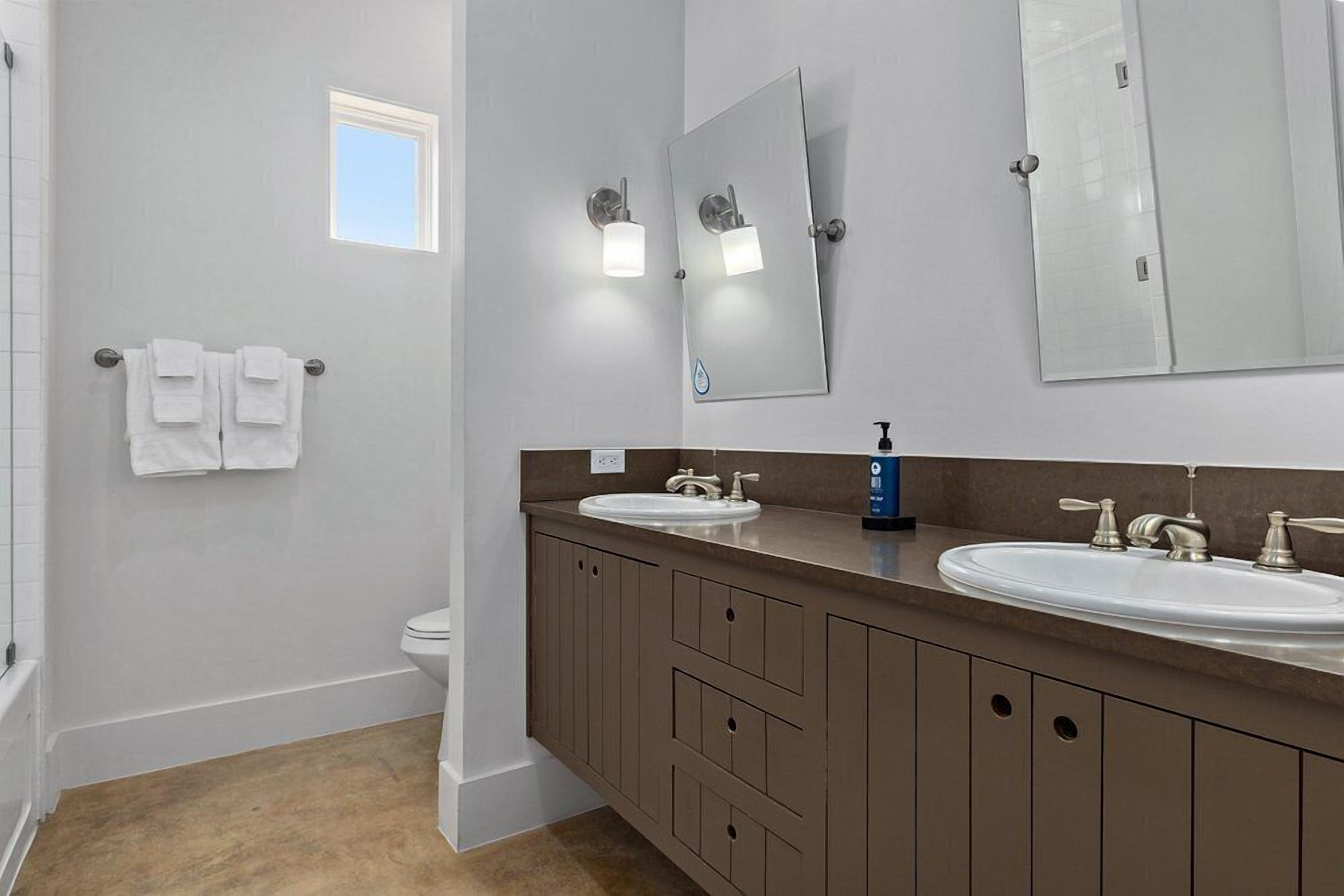 Une salle de bain avec deux lavabos, des toilettes, une douche et un miroir.