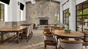 A rustic interior with stone walls, a fireplace, and multiple seating areas. - Hill Country | Group Nature Retreat | Pool + Trails | 3BR Sleeps 10 (Hunt)