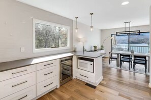 Eine moderne Küche mit weißen Schränken, einem eingebauten Ofen und einem großen Fenster mit Blick auf eine verschneite Landschaft.