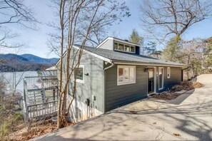 A single-story house with a dock, a garage, and a view of a lake and mountains. - Lake Lure Modern Retreat | Marina Access + Views (Lake Lure)