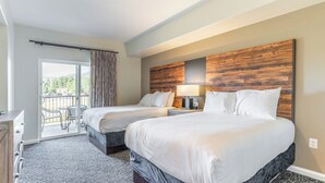 Une chambre d’hôtel avec deux lits, un balcon offrant une vue, une tête de lit en bois et un bureau.