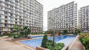 Un edificio residencial de varios pisos, una piscina y zonas verdes circundantes.