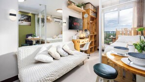 Un dormitorio moderno con cama, escritorio, televisor y vistas al exterior.