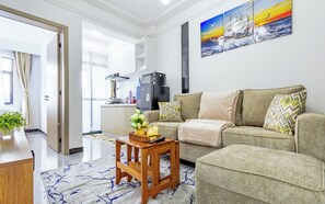 A modern living room with a sofa, a small wooden table, and a kitchen in the background. - Kilimani Urban Retreat – Near Yaya (Nairobi)