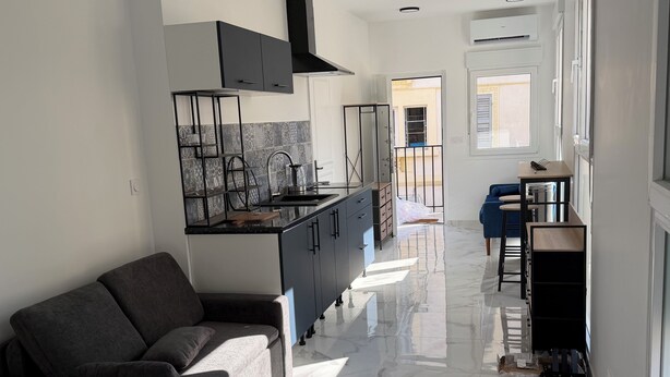Une cuisine moderne avec un sol en marbre, un canapé et un coin repas comprenant une table et des chaises.