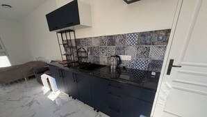 Une cuisine moderne avec un plan de travail noir, des armoires blanches et un dosseret à motifs.