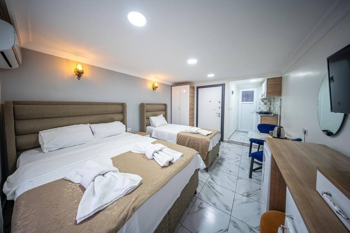 A hotel room with two beds, a desk, a chair, a mirror, and a bathroom.