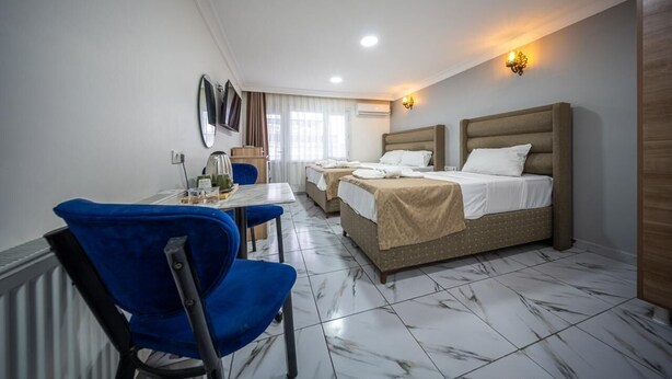 Habitación de hotel con dos camas, un escritorio con silla, televisión y baño con ducha.