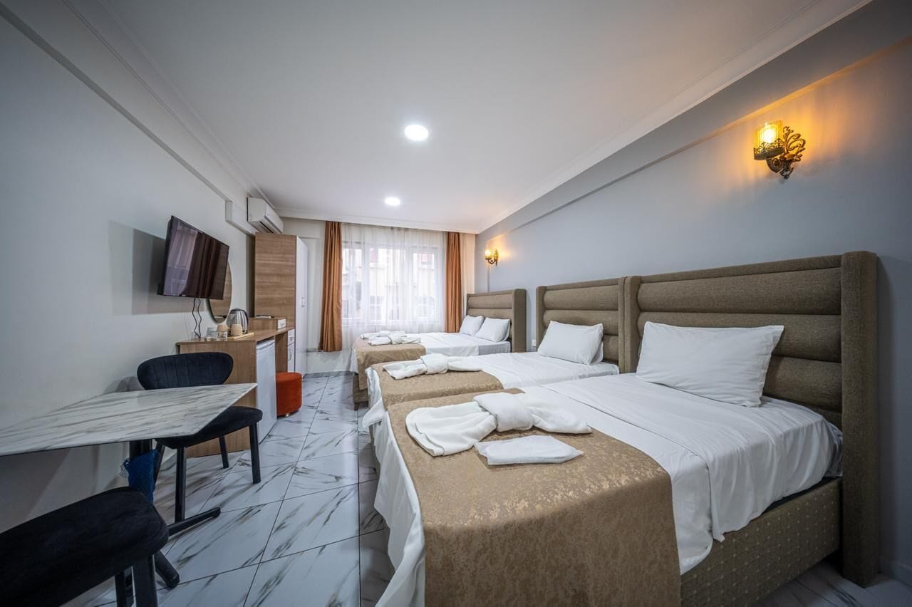 Ein Hotelzimmer mit Bett, Nachttischen, Schreibtisch, Stuhl und Fernseher.