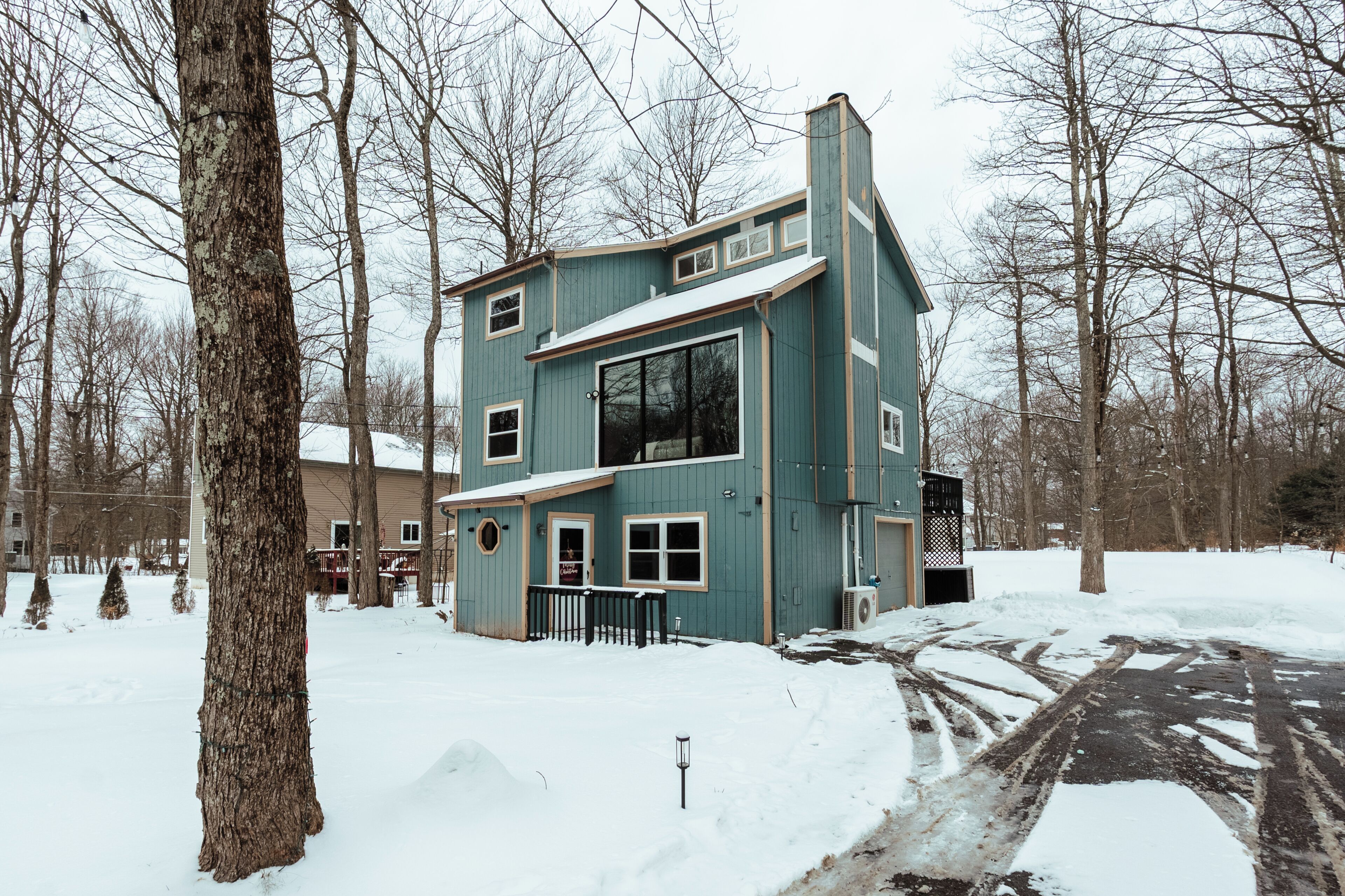 Une maison à deux étages, avec un toit en pente, de nombreuses fenêtres et une cheminée bien visible.