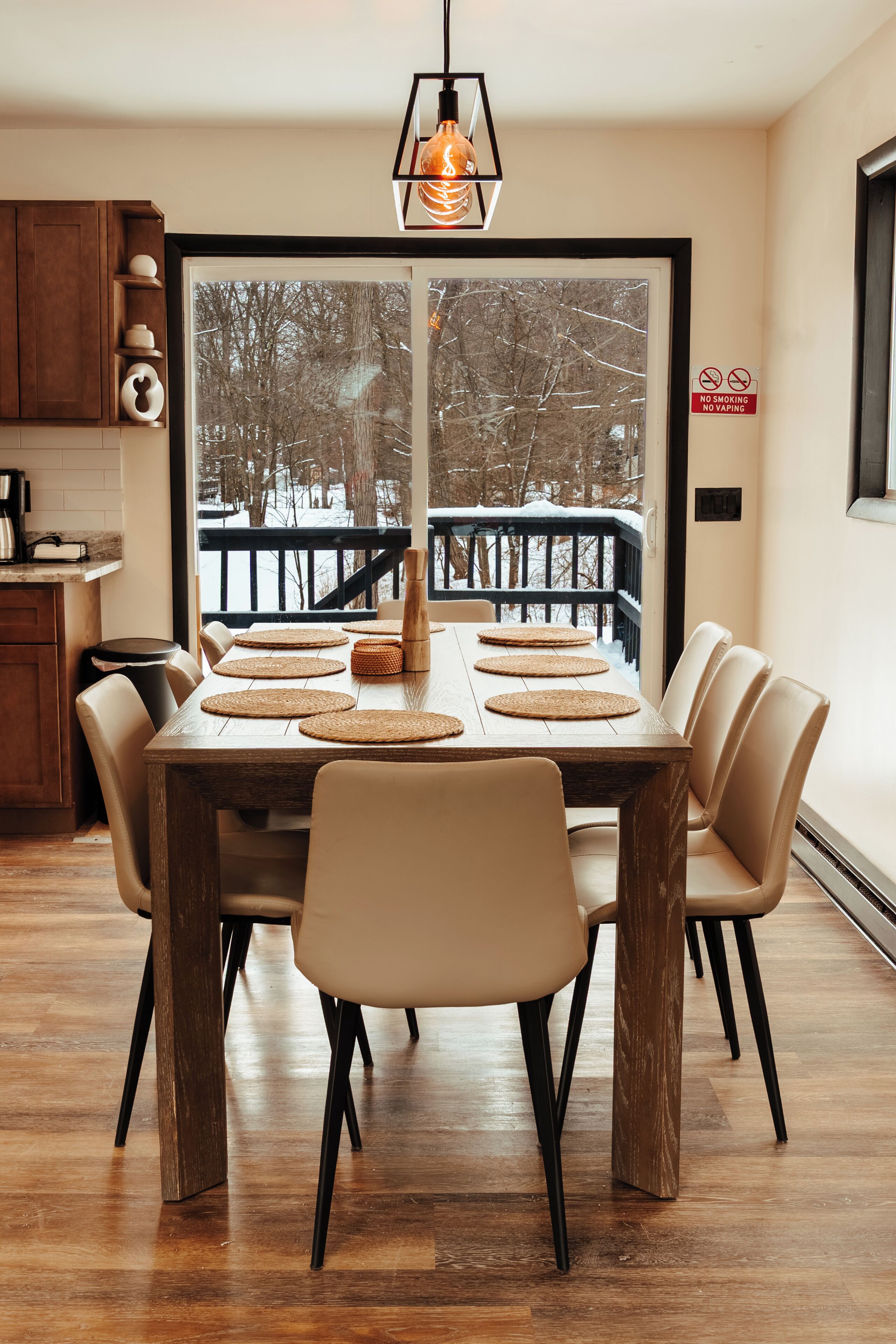 A dining area with a wooden table, beige chairs, and a view of a snowy outdoor deck.