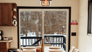 Ein Essbereich mit einem Holztisch, beigen Stühlen und Blick auf eine verschneite Terrasse.