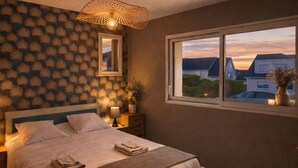 Ein Schlafzimmer mit einem großen Bett, einem Fenster mit Ausblick, einer Wand mit Muster und einer hängenden Leuchte.