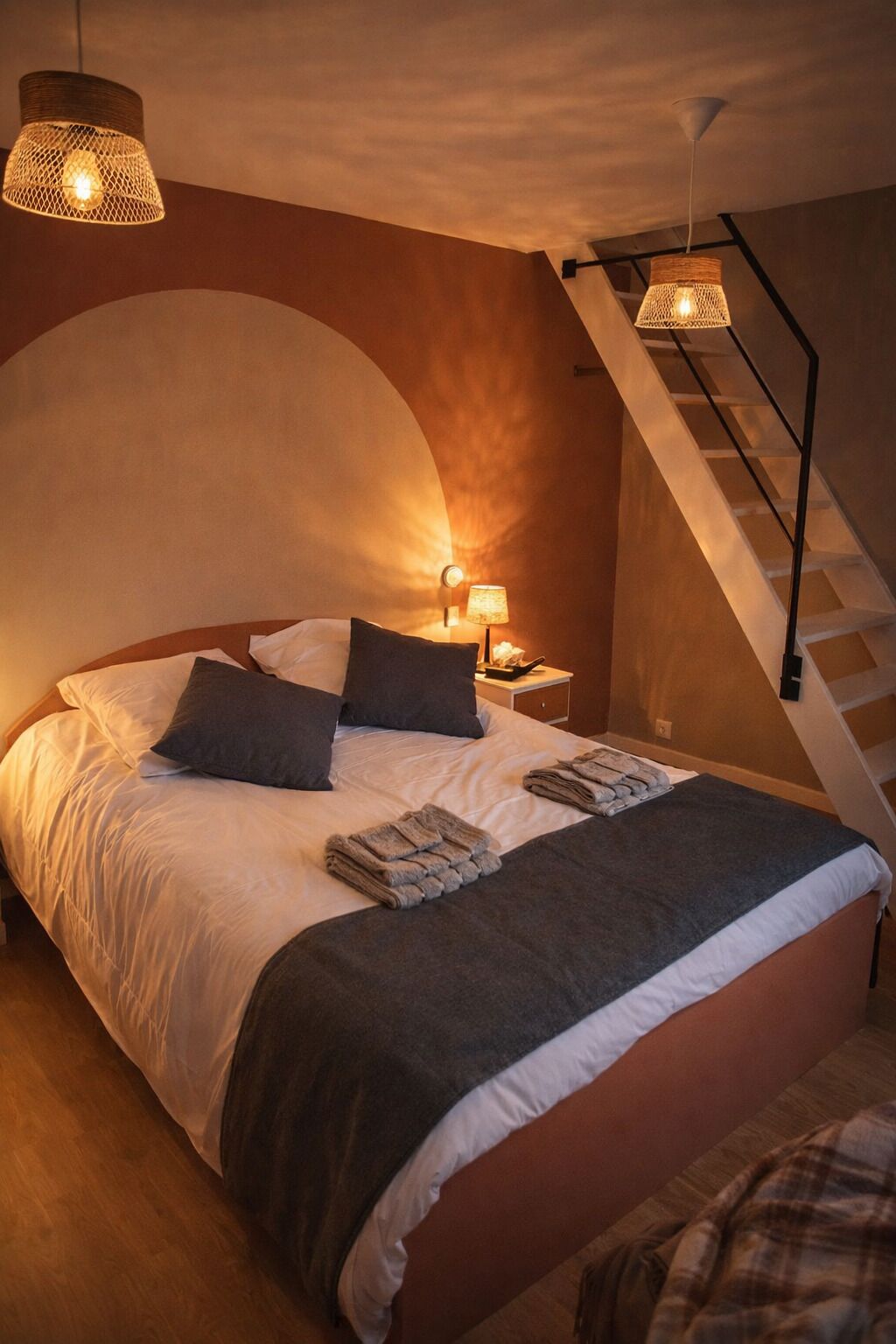 Un dormitorio con una cama, dos lámparas de noche, una mesita de noche y una escalera.