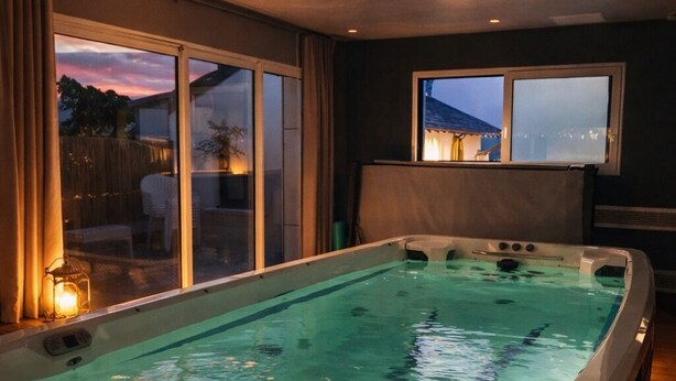 Ein Whirlpool mit Blick auf den Sonnenuntergang, ein Fenster und eine Kerze auf dem Boden.