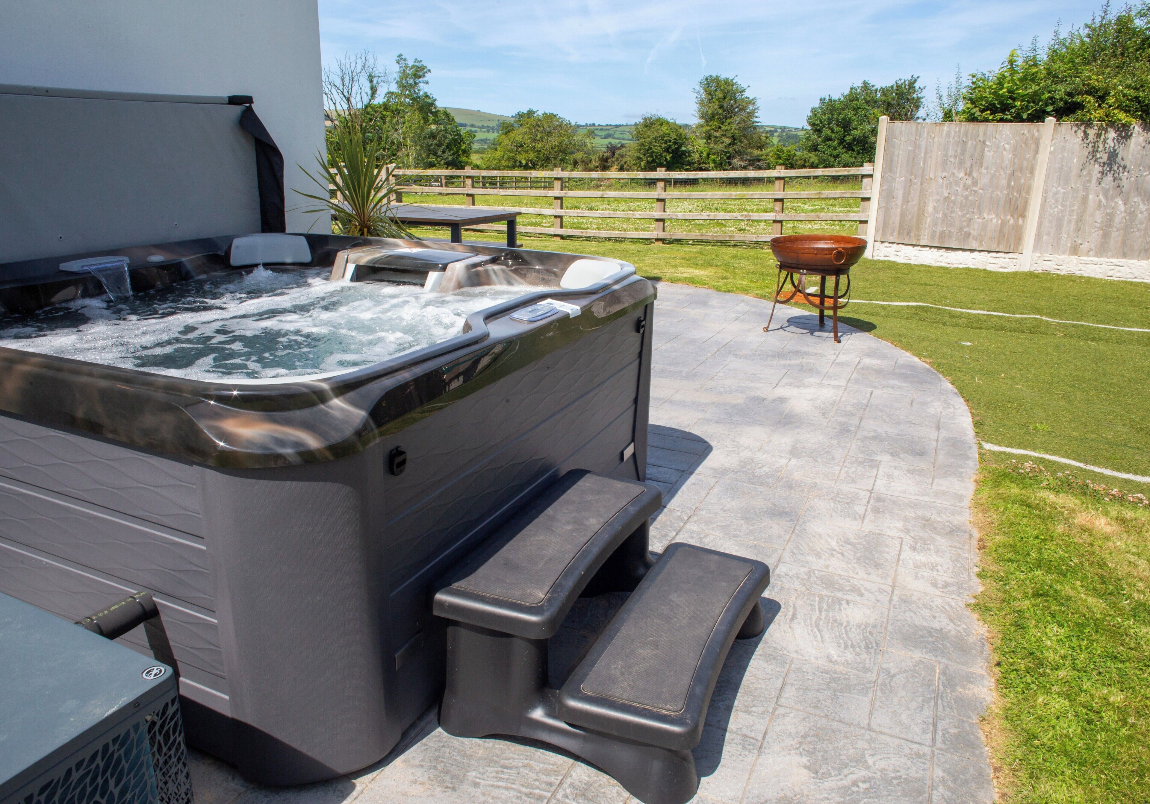 A hot tub with steps, a wooden fence, and a grassy yard.