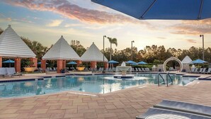 A pool area with lounge chairs, umbrellas, and a fountain. - 1 Bedroom Condo, Sleeps 4, SeaWorld Hilton Grand Vacations (Orlando)