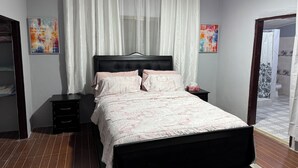 Un dormitorio con cama, mesita de noche, armario y dos cuadros en las paredes.