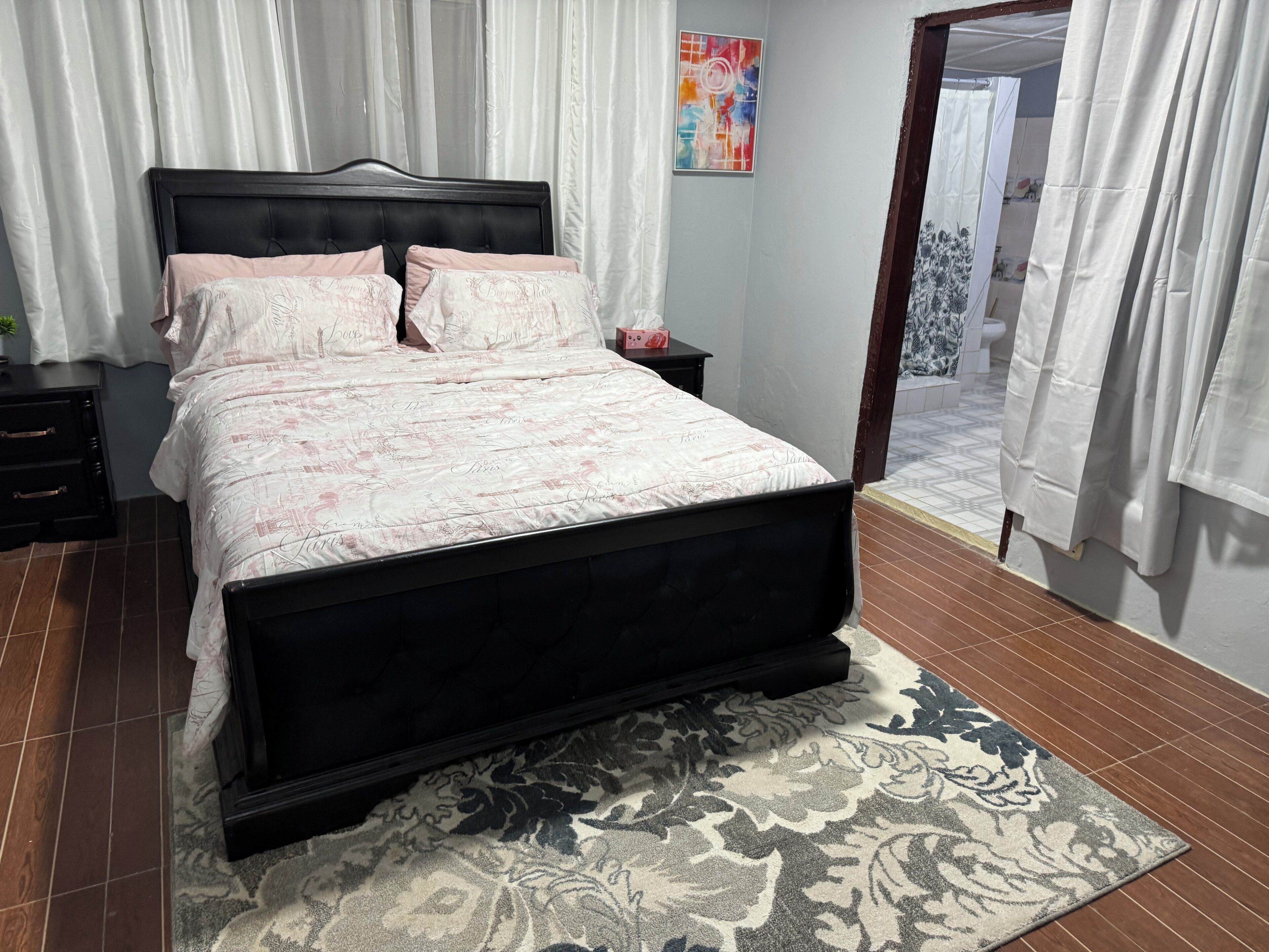 A bedroom with a bed, nightstands, a rug, and a door leading to a balcony.