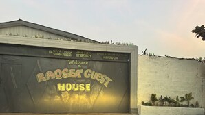 Un edificio con un letrero que dice 'RAOSEASE GUEST HOUSE' e información de contacto.