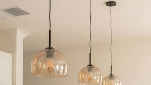 Una cocina moderna con iluminación colgante, encimera de mármol y un jarrón con plumas de plumero.