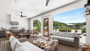 A spacious outdoor living area with a kitchen, seating, and a view of the surrounding landscape. - Sugar Magnolia: Close to beach in Grayton w/ Pool!  4 Kings + 6 Bunks; sleeps 14 (Santa Rosa Beach)