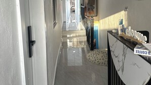 Un pasillo con mostrador de recepción, una obra de arte enmarcada y una escalera que conduce a otra zona.