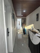 A hallway with a reception desk, a framed artwork, and a staircase leading to another area.