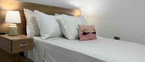 Ein Schlafzimmer mit einem Holzkopfteil, einem Nachttisch mit Lampe und einem Bett mit weißer Bettwäsche.