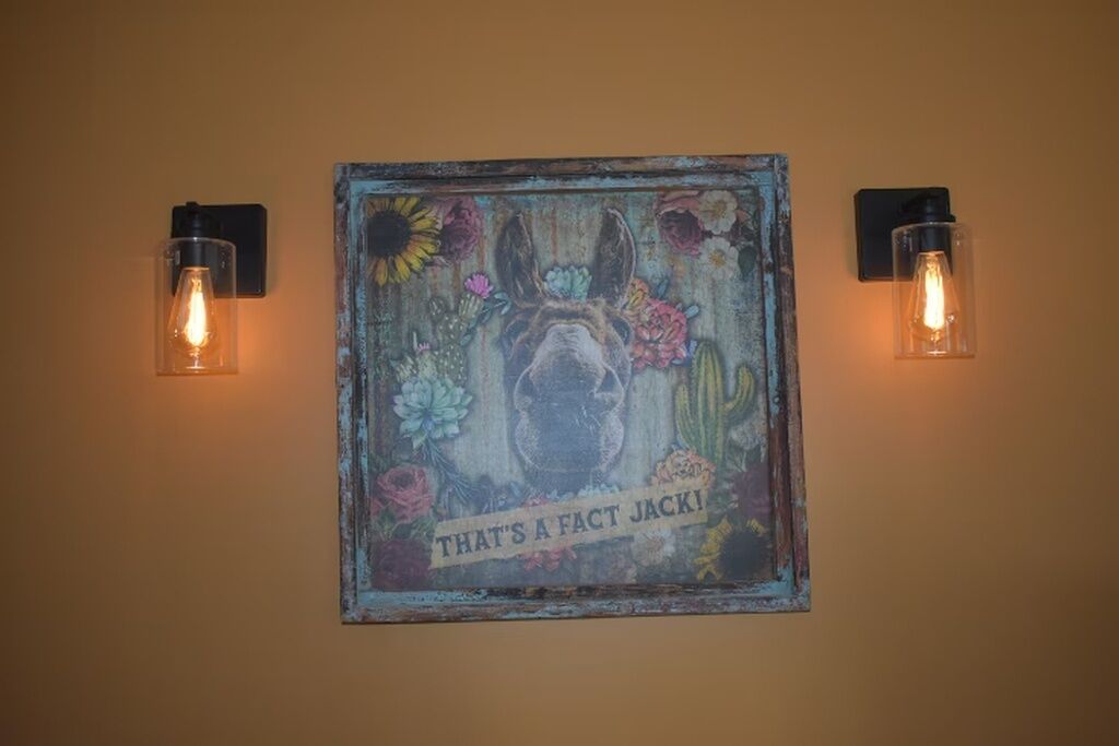 A wall-mounted artwork with a dog and text, flanked by two wall-mounted light fixtures.