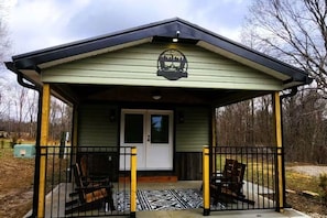 A small, single-story building with a porch, a door, and a logo above the entrance.