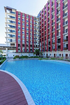 Un hotel de varios pisos con balcones, piscina y jardín ajardinado.