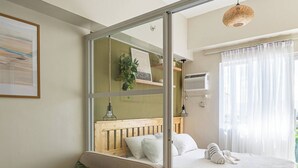 Una habitación con sofá, cama, mesa de madera y lámpara colgante.