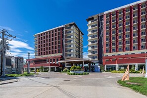 Ein modernes Hotel mit mehreren Etagen, einem zentralen Innenhof und einem überdachten Eingang.