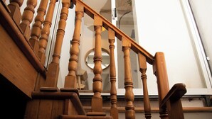 Una escalera de madera con barandilla y un espejo redondo en la pared.