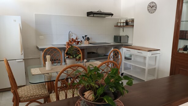 A modern kitchen with a dining area, white tiled backsplash, and a clock on the wall. - La palma Great Location Spacious Funtonal Equipied (Cancún)